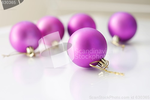 Image of Purple  Christmas baubles on a glass table.