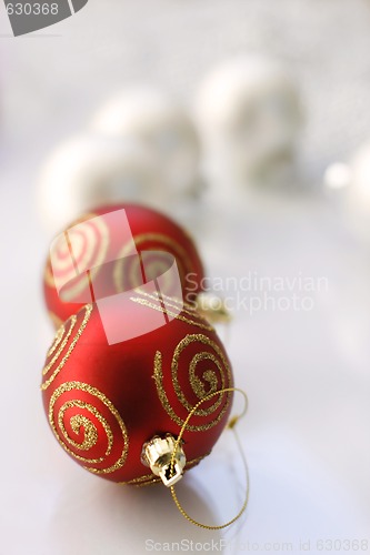 Image of Red and silver colored Christmas baubles on a glass table.