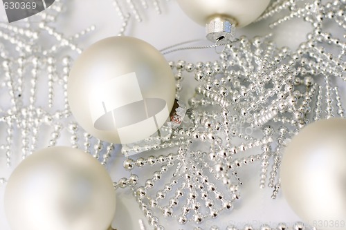 Image of Silver colored Christmas baubles on glass table.