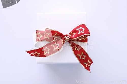 Image of Christmas gift in white wrapping and red ribbon.