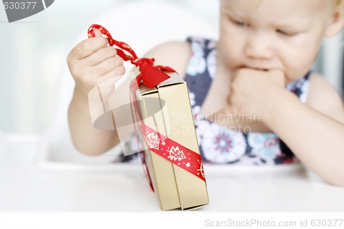 Image of Little girl carefully opening Christmas gifts.
