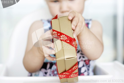 Image of Little girl carefully opening Christmas gifts.