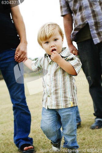 Image of hild walking with parents in a park.