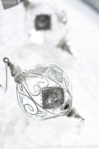 Image of Sparkly silver colored Christmas baubles on glass table.