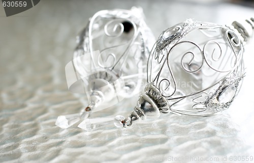 Image of Sparkly silver colored Christmas baubles on glass table.