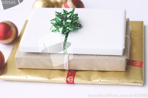 Image of Three simply wrapped Christmas gifts with decorations.