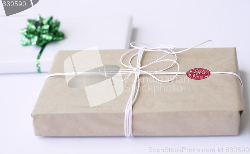 Image of Two simply wrapped gifts with decorations.