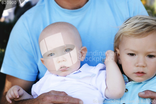 Image of Two little boys in their father’s lap.