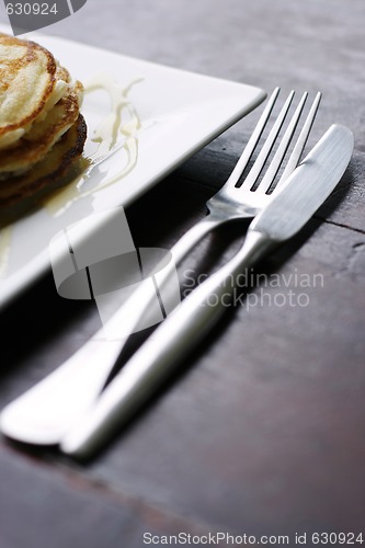 Image of Knife and fork next to a stack of pancakes.
