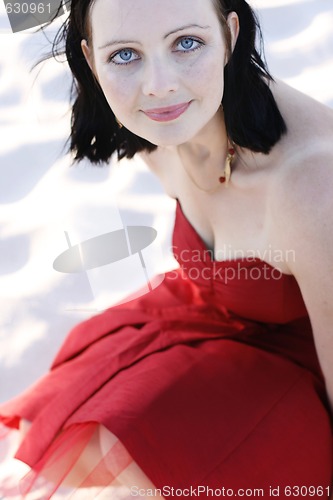 Image of Portrait of a beautiful woman in a red dress outdoors.