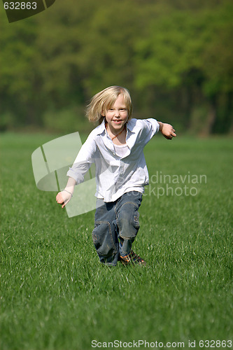 Image of little, blond boy laughing and running through a meadow