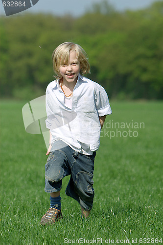 Image of blond boy laughing and running through a meadow