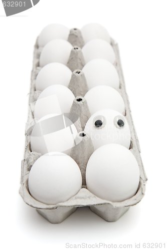 Image of Funny egg with eyes among dozen in a paper box