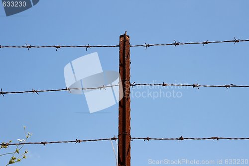 Image of Three strands of barbed wire on rusty post over sky  background