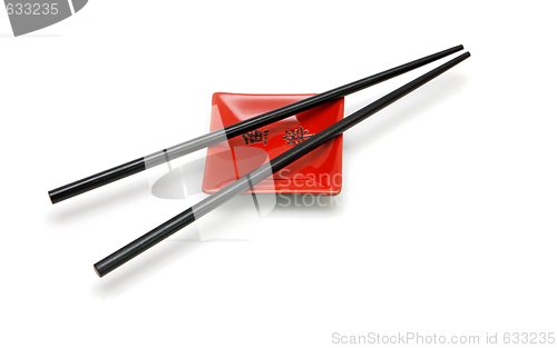 Image of Chopsticks on  small red square saucer with kanji inscription isolated