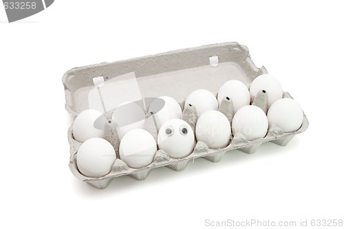 Image of Funny egg with eyes among dozen in a paper box isolated