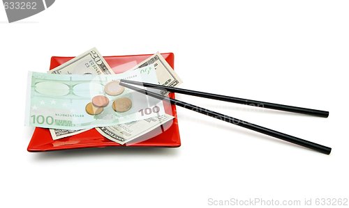 Image of Money bills and coins on red square plate with chopsticks isolated