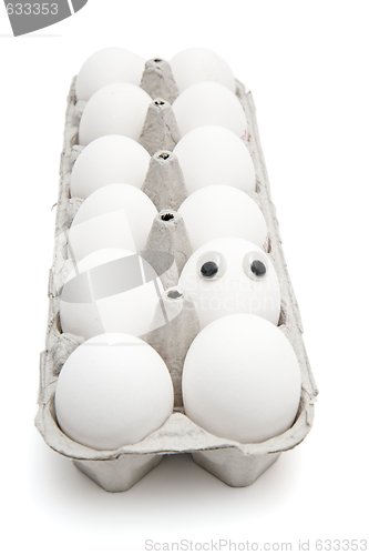 Image of Funny egg with eyes among dozen in a paper box isolated