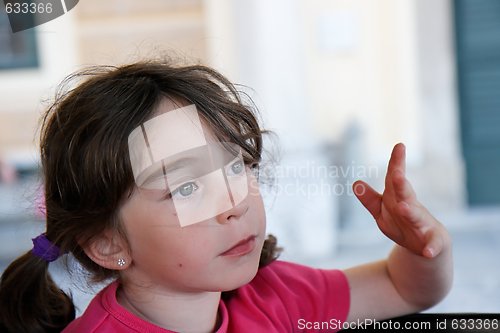 Image of Cute serious seven years girl gestures with her hand