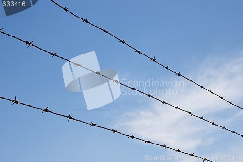 Image of Three strands of rusty barbed wire over sky 