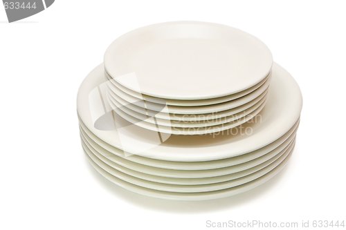 Image of Stack of plain beige dinner plates and saucers isolated