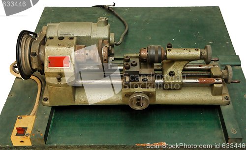 Image of Small metal lathe on green board isolated 