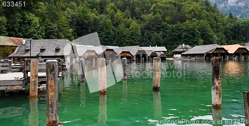 Image of Wooden boat houses and mooring posts on green lake water