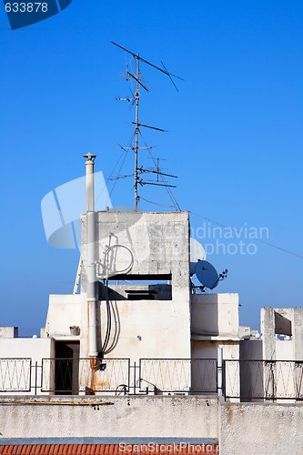 Image of Old television aerial on house roof against blue sky