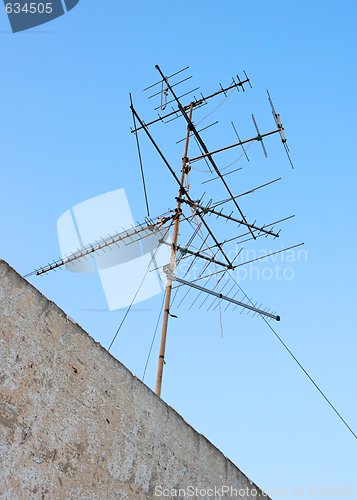 Image of Old television aerial on roof against blue sky