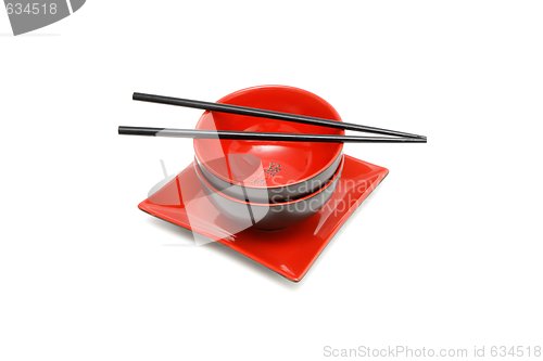 Image of Black chopsticks on red and black Japanese bowl and square plate isolated