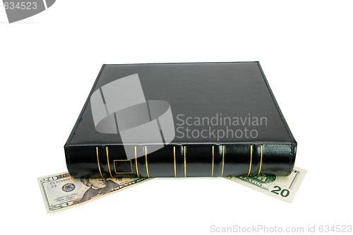 Image of Thick black book on twenty dollar bills isolated