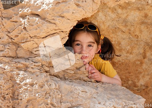 Image of Cute little girl hides behind a rock