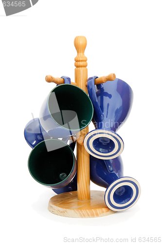 Image of Four blue coffee cups hanging on wooden rack isolated