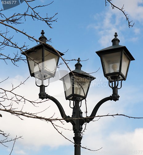 Image of Retro street lantern and tree branches over cloudy sky