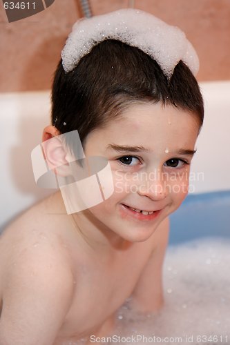 Image of Cute little boy in a bathtub with foam cap on his head