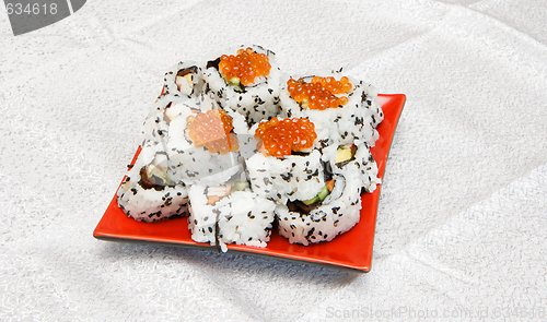 Image of Homemade inside-out maki sushi with red caviar on red square plate 