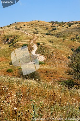 Image of Countryside road leads to the top of yellow autumn hill