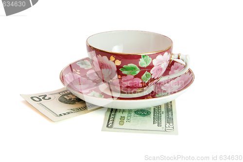 Image of Tea cup and saucer on twenty dollar bills isolated