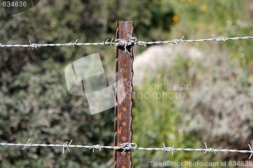 Image of Two strands of barbed wire fence on rusty steel post