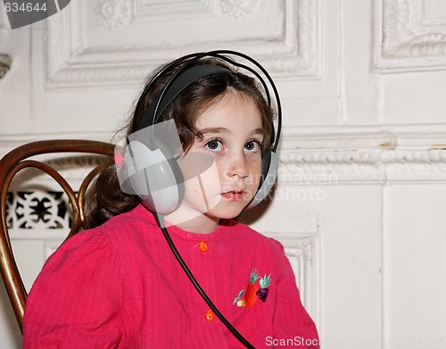 Image of Cute little seven years girl listens to music in earphones