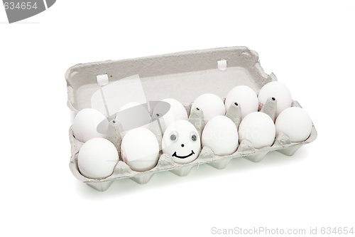 Image of Funny egg with eyes among dozen in a paper box isolated