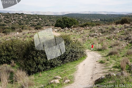 Image of Lonely little boy walks along the trail among hills outdoor