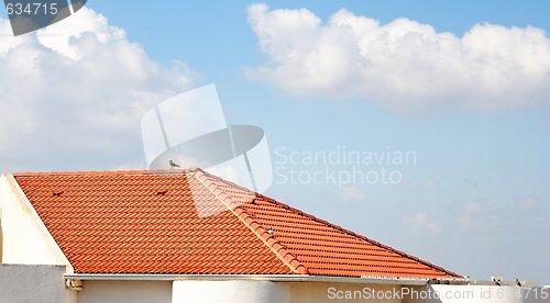 Image of Orange tiled roof under the cloudy blue sky 