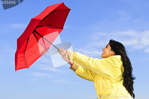 Image of Beautiful young woman in raincoat with umbrella