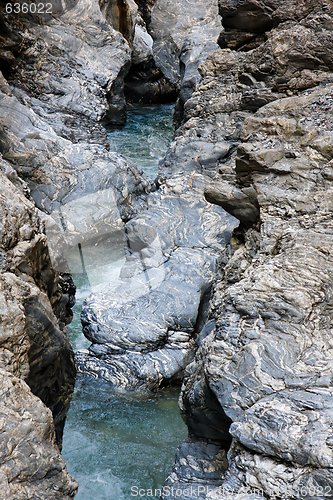 Image of Narrow mountain stream flows among blue striped rocks