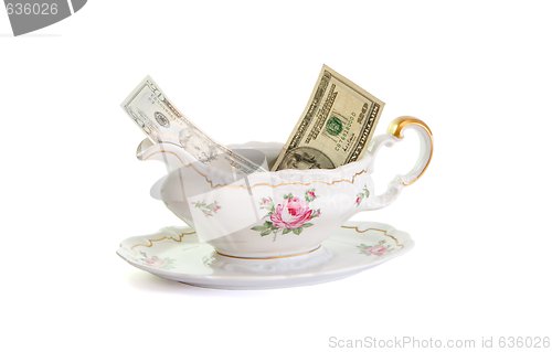 Image of Vintage porcelain sauce-boat with dollar bills isolated 