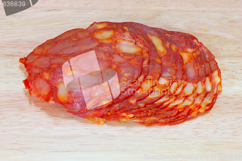 Image of sliced salami on wooden plate