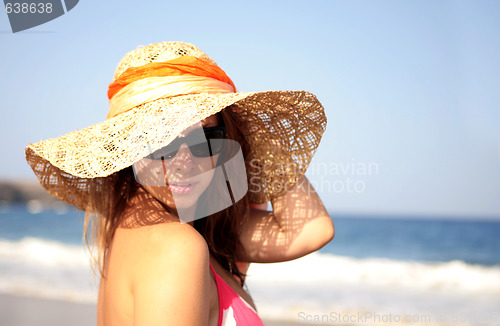 Image of beautiful woman standing by the sea in a  hat 