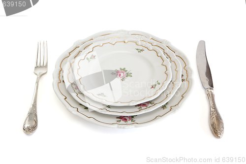 Image of Dinner set with three plates, knife and fork isolated
