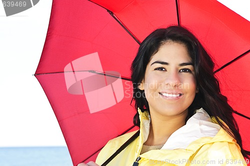 Image of Beautiful young woman in raincoat with umbrella